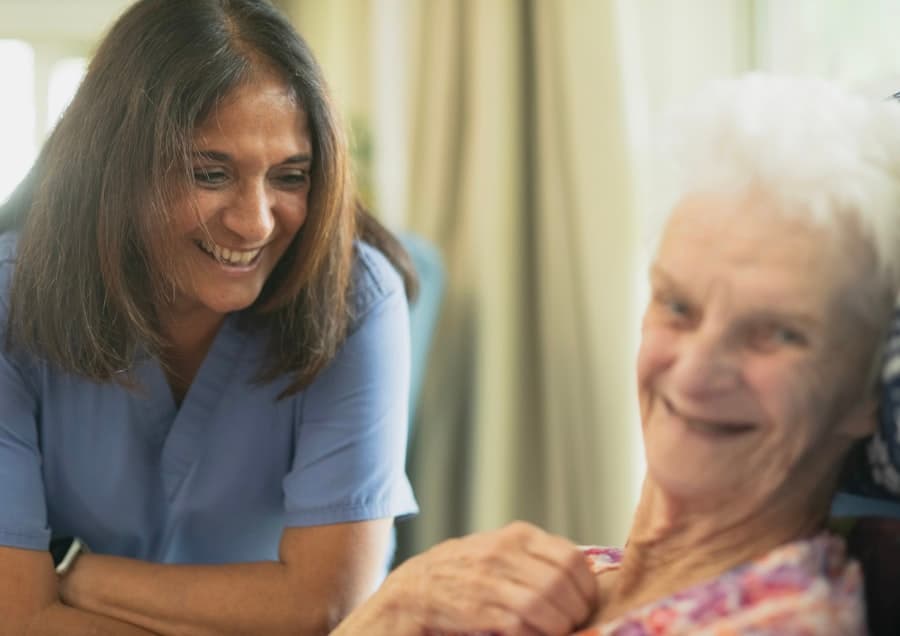 A caregiver laughing with an elderly resident in a care home