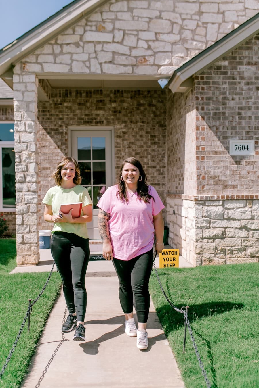 A caseworker and client walking out of a house together, smiling